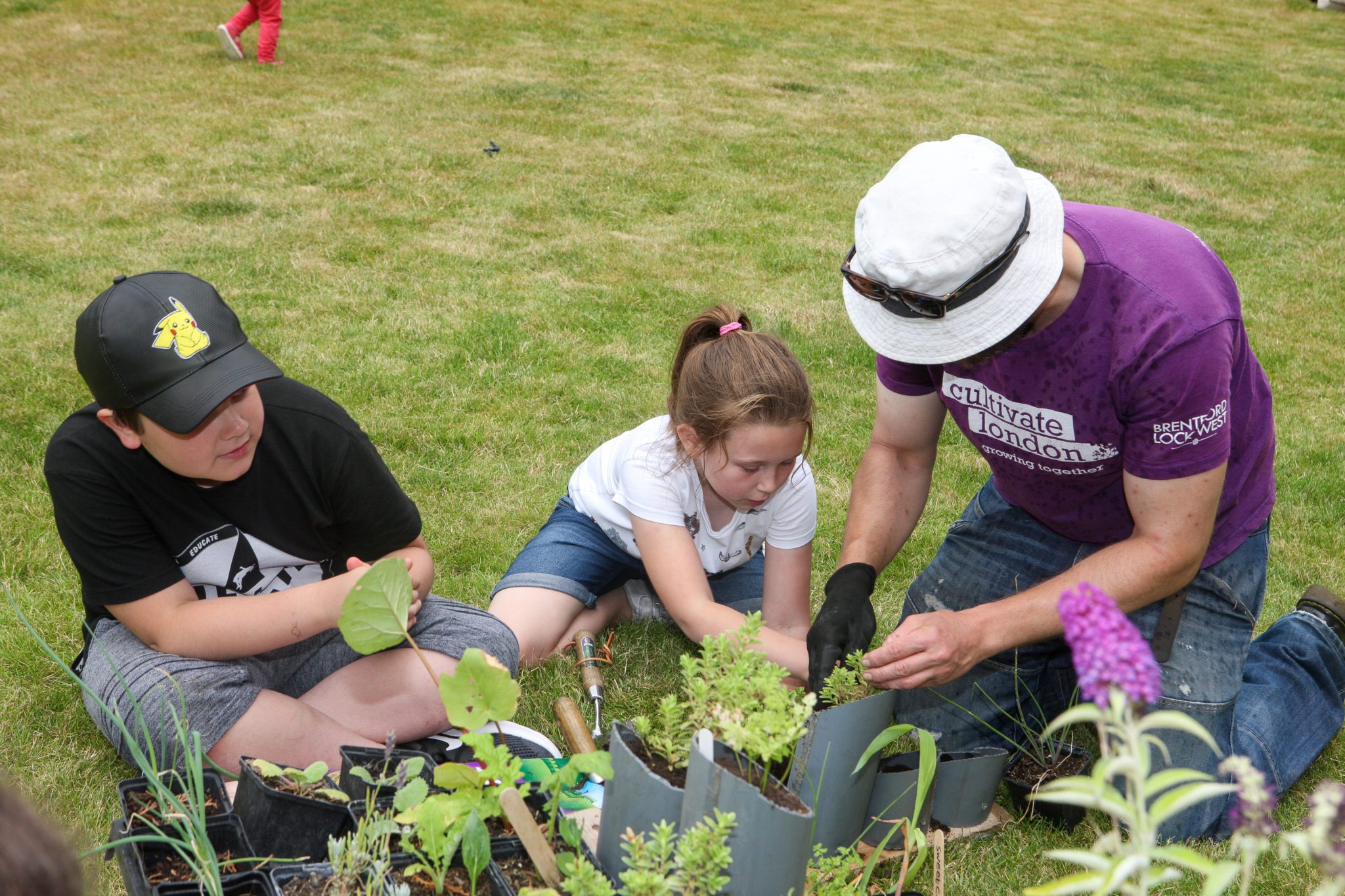 Man showing children how to pot a plant