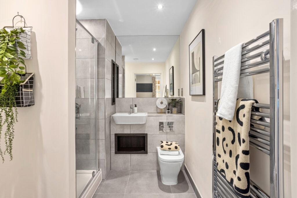 En suite with shower, sink, toilet and dark brown shelving
