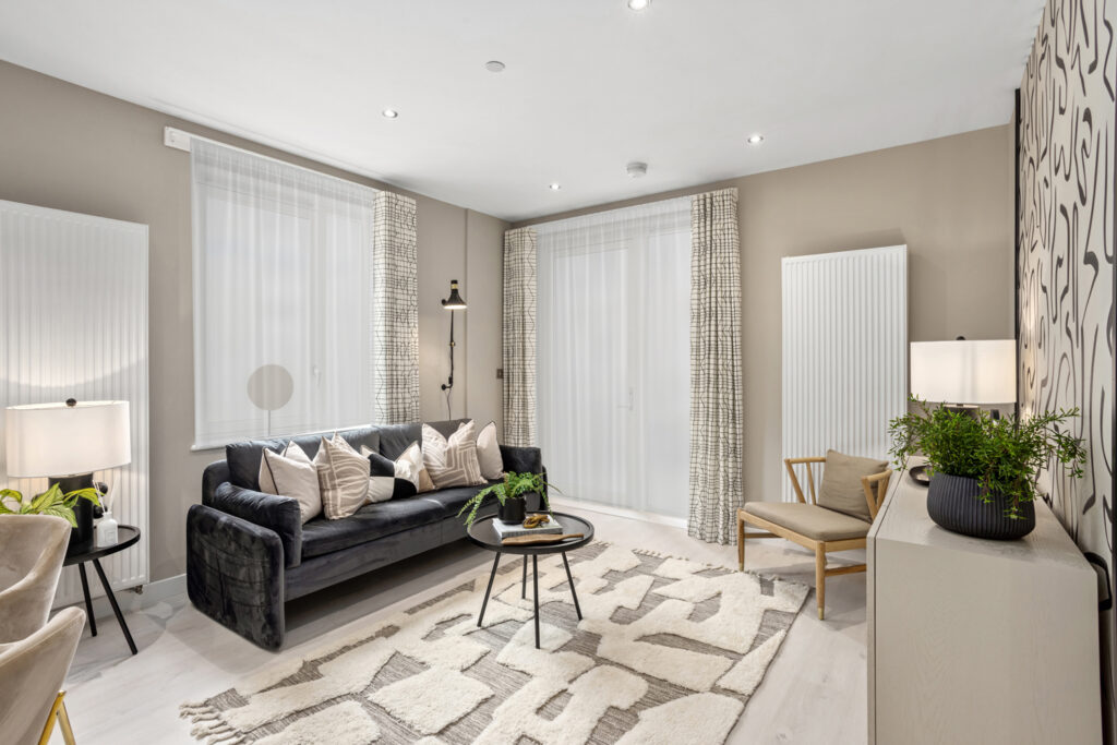 Dark coloured couch with circular coffee table and cream decorations.