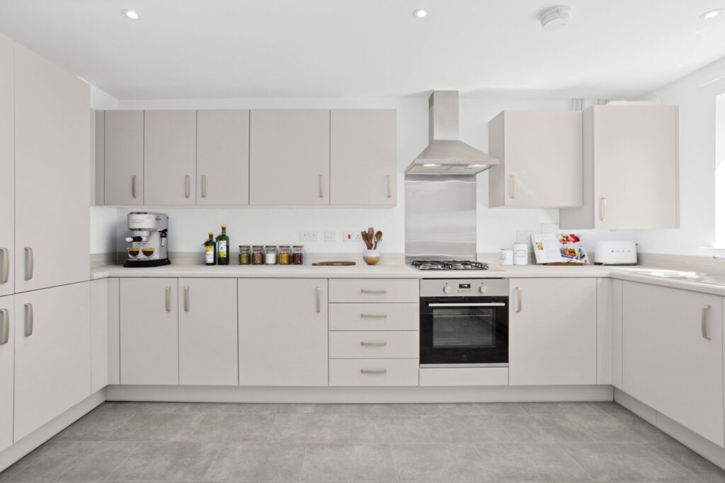 Modern fitted kitchen with integrated oven and hob, light-coloured cabinetry, and ample worktop space.