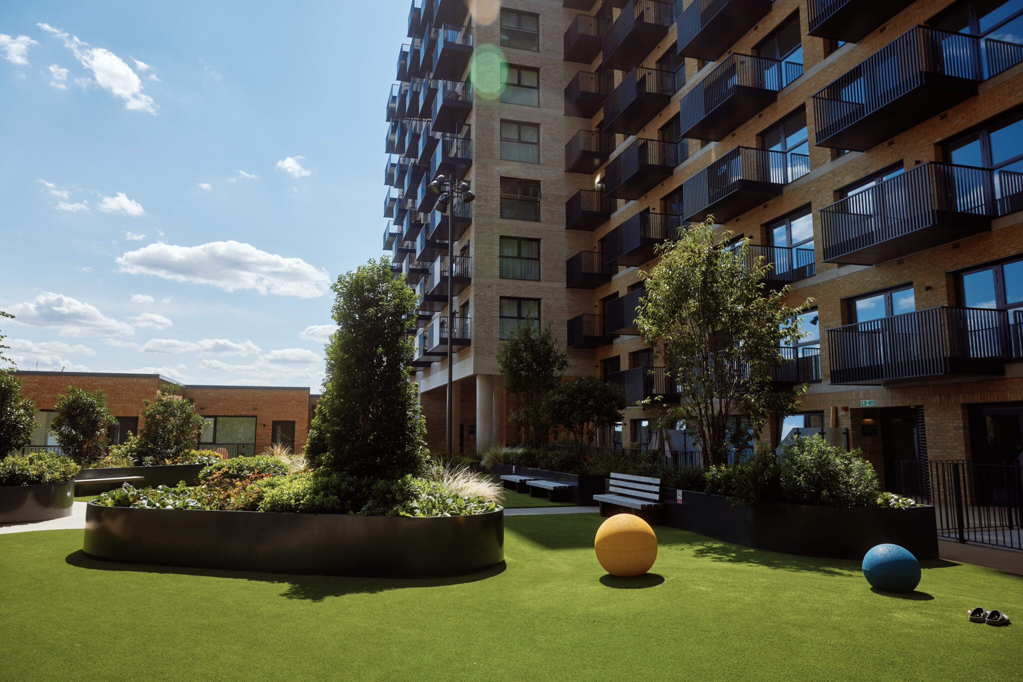 Podium gardens with landscaped areas and Kew Bridge Rise to the side.
