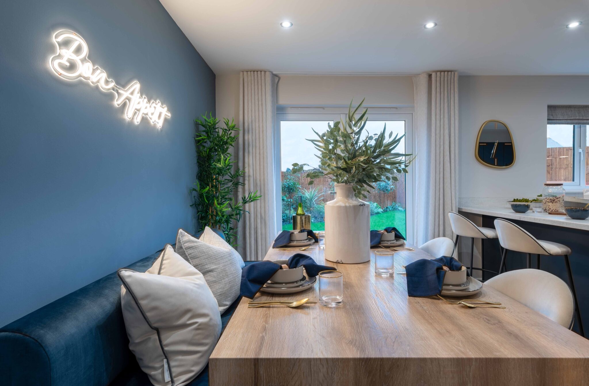 Dining table, breakfast bar and french doors to rear garden of show home.