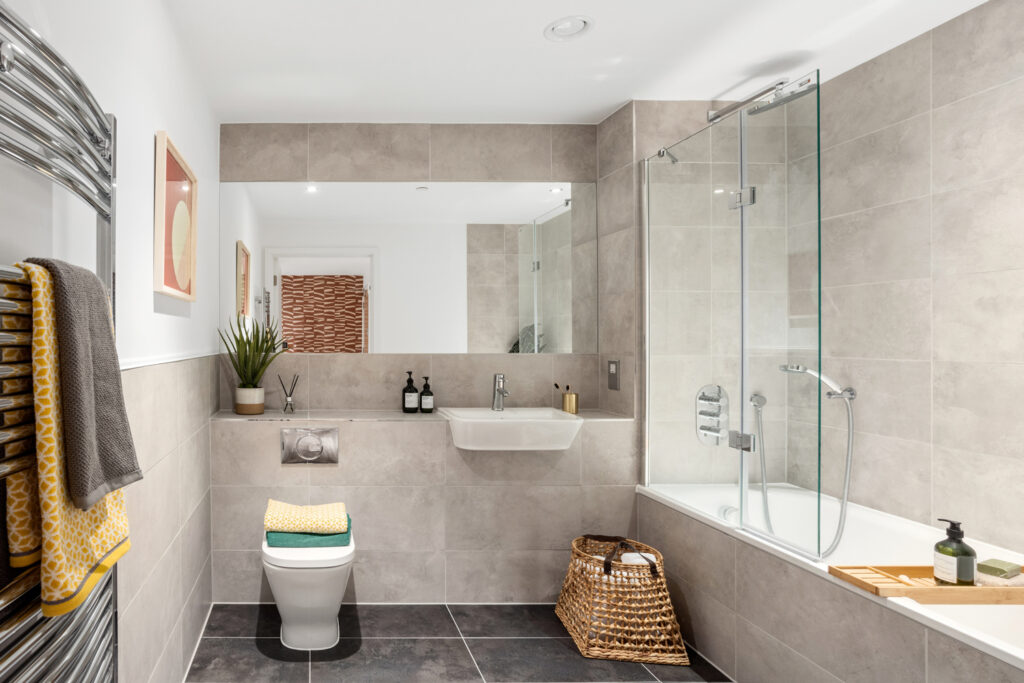 Bathroom with bath, toilet, sink, hamper with towels and hanging towels on the left