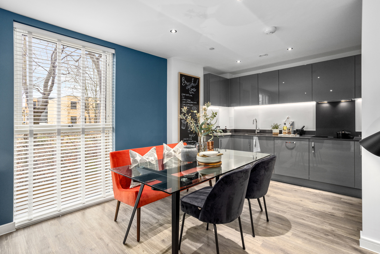 A dark grey kitchen with full appliances and dinning table and chairs in front